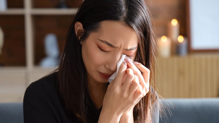 Een chinese vrouw is aan het huilen en probeert met een wit zakdoekje haar tranen weg te vegen